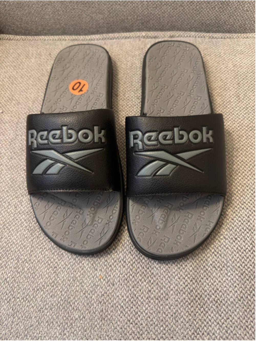 Reebok black slide sandals with the iconic vector logo embossed on the strap